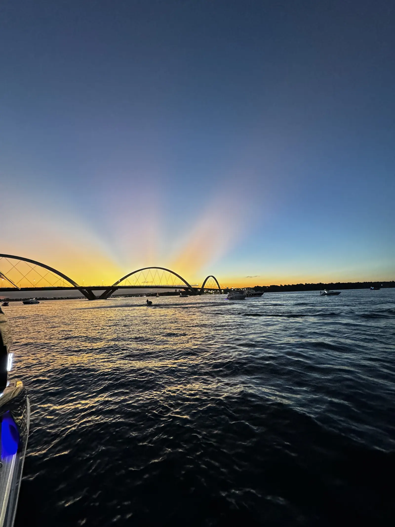 Lancha e Jet Ski no Lago Paranoá durante o pôr do sol, com a Ponte JK
